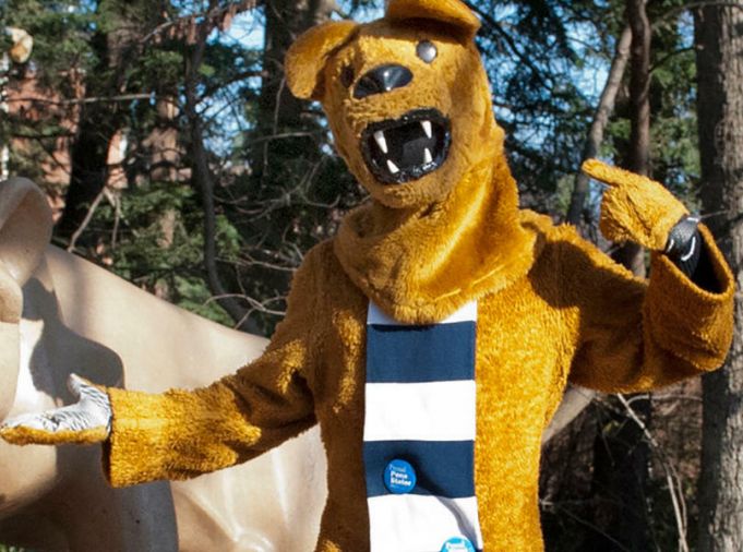 Nittany Lion mascot posing with Lion Shrine statue.