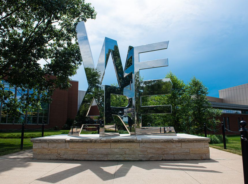 Decorative public sculpture of the words "WE ARE" in mirror material.